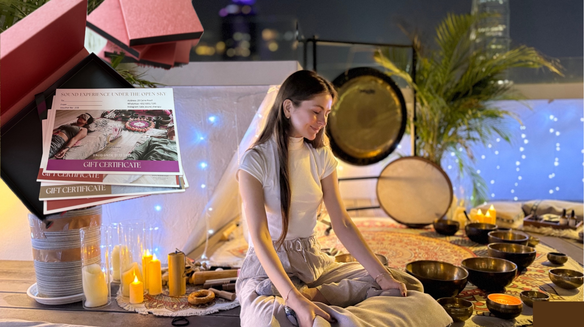 Kate Mormylo seated with Tibetan singing bowls and a wellness gift certificate box on a hidden rooftop in Central, Hong Kong at night, with the city skyline glowing behind her